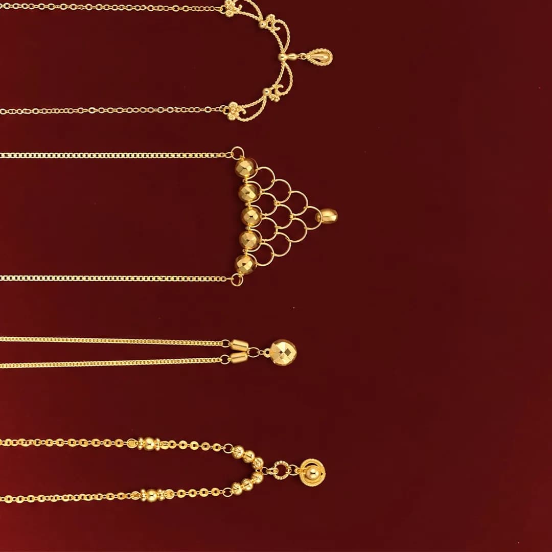 Five gold chains with pendants on a burgundy background